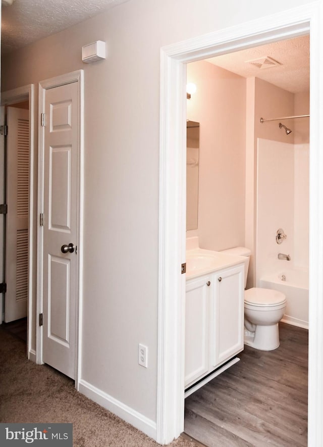bathroom featuring bathing tub / shower combination, visible vents, toilet, vanity, and a textured ceiling