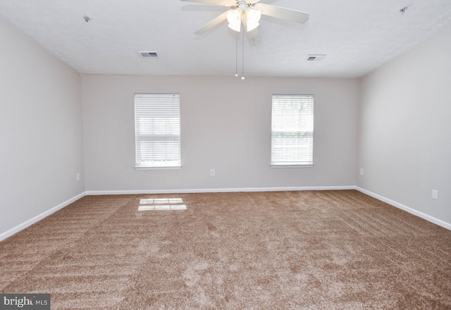 spare room featuring carpet floors, visible vents, a ceiling fan, and baseboards