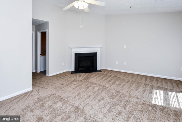unfurnished living room featuring a fireplace with flush hearth, carpet floors, baseboards, and ceiling fan
