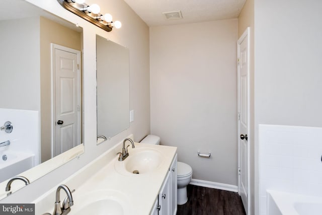 bathroom with a garden tub, wood finished floors, a sink, and visible vents