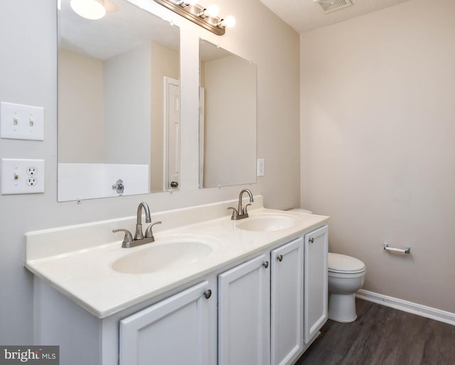 full bath featuring double vanity, wood finished floors, toilet, and a sink