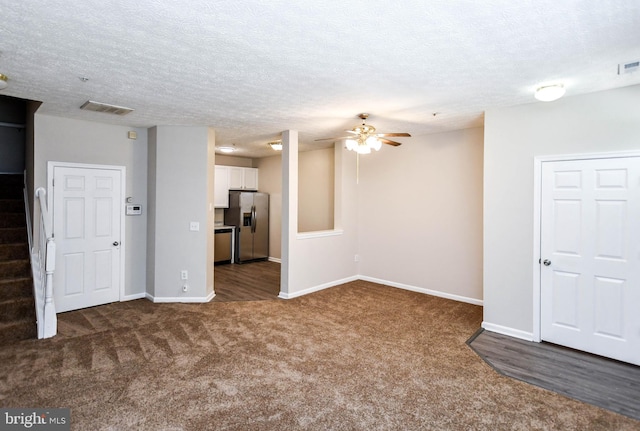 unfurnished living room featuring dark carpet, visible vents, baseboards, and ceiling fan