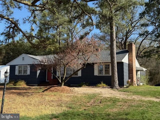 single story home with a chimney and a front lawn