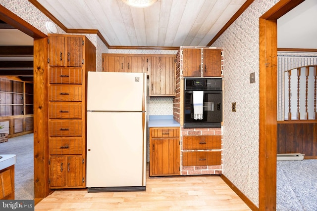 kitchen featuring freestanding refrigerator, black oven, crown molding, and brown cabinetry
