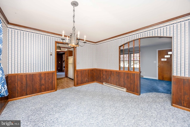 spare room with an inviting chandelier, a wainscoted wall, ornamental molding, and baseboard heating