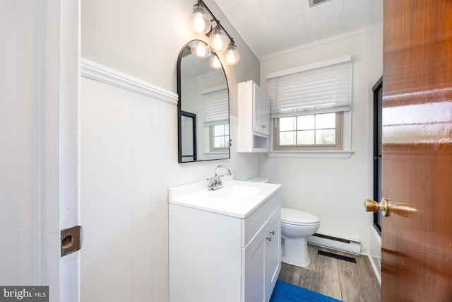 full bath with crown molding, baseboard heating, wood finished floors, vanity, and toilet