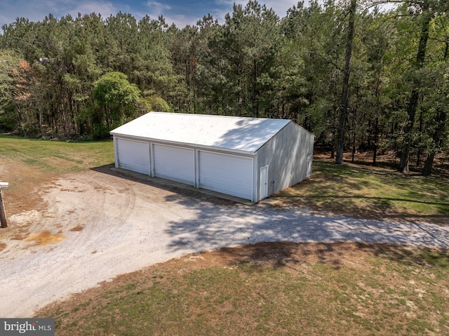 detached garage featuring a view of trees