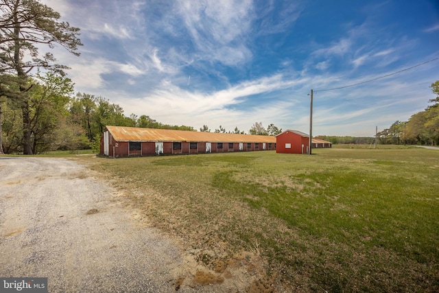 view of front facade with a front lawn, an outbuilding, and driveway