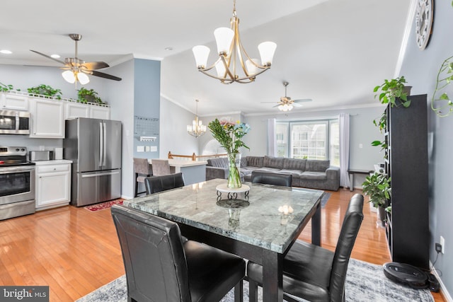 dining room featuring light wood finished floors, vaulted ceiling, crown molding, and ceiling fan with notable chandelier