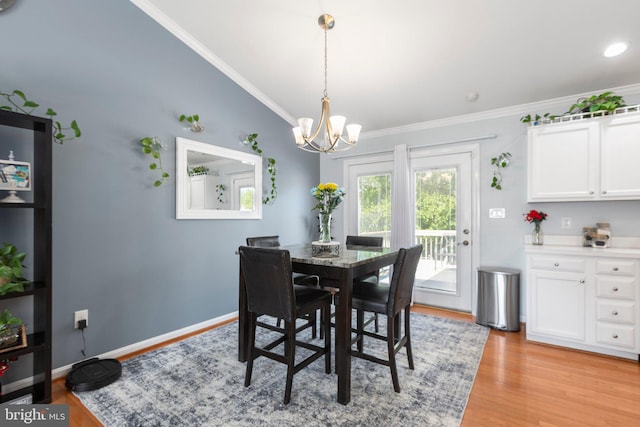 dining space with light wood-style flooring, crown molding, baseboards, and a notable chandelier