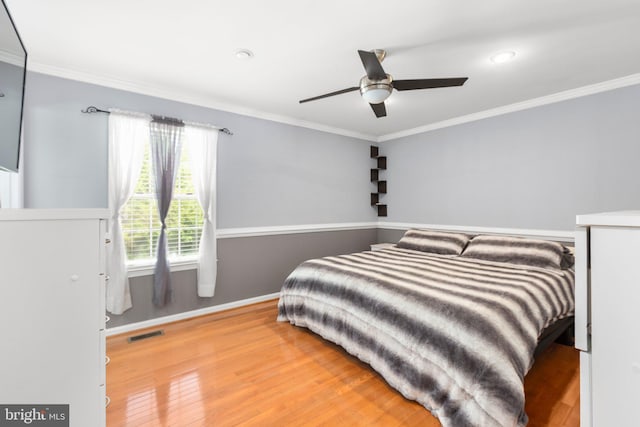 bedroom with visible vents, wood finished floors, and ornamental molding
