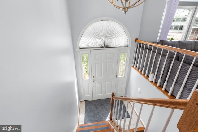 carpeted entryway with a chandelier