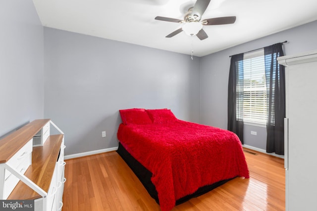 bedroom featuring light wood-type flooring, baseboards, ceiling fan, and visible vents