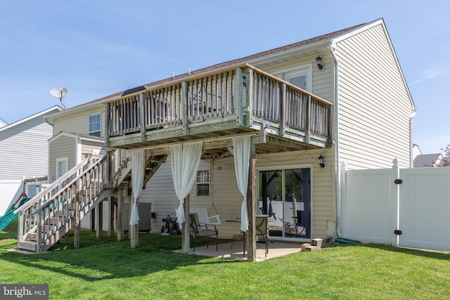 rear view of house featuring fence, a lawn, stairs, and a patio