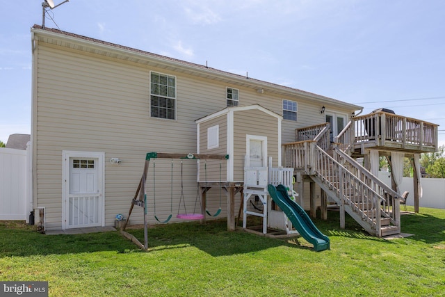 rear view of house featuring fence, a deck, a yard, and a playground