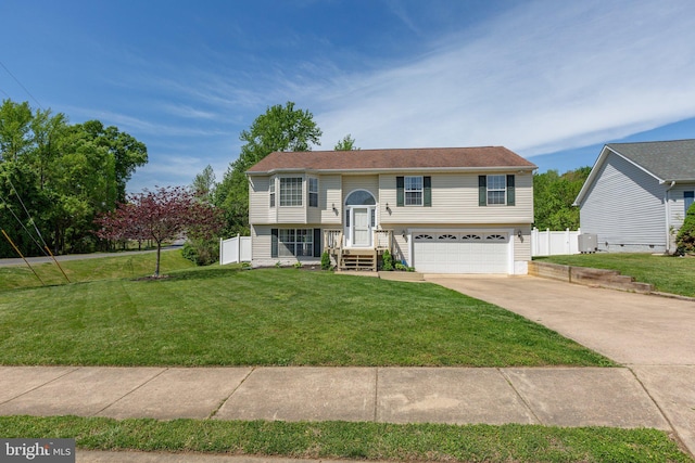 bi-level home featuring fence, driveway, a front yard, and a garage