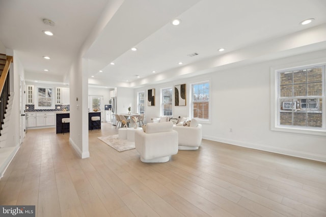 unfurnished living room with visible vents, recessed lighting, stairway, light wood finished floors, and baseboards