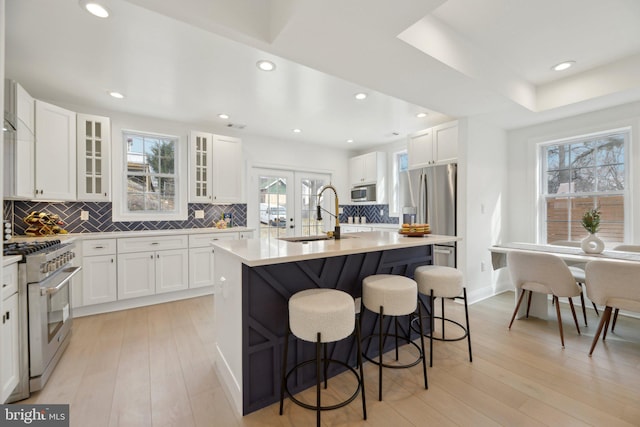 kitchen featuring light wood-style flooring, appliances with stainless steel finishes, a sink, and a breakfast bar