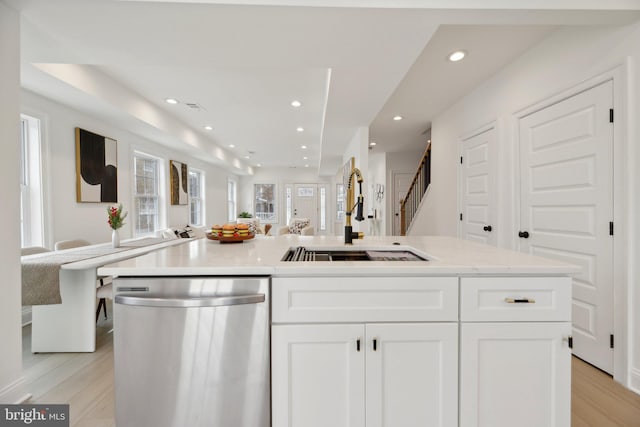 kitchen featuring recessed lighting, white cabinets, light wood finished floors, dishwasher, and a sink