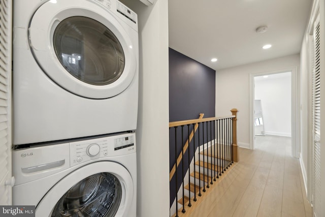 laundry area with baseboards, stacked washer / dryer, laundry area, recessed lighting, and wood finished floors