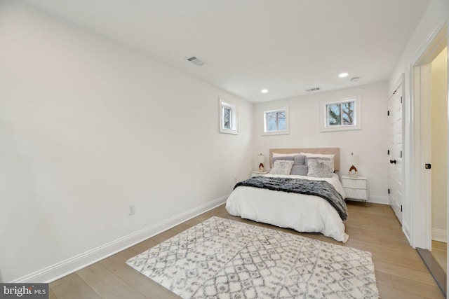 bedroom with light wood finished floors, baseboards, and visible vents