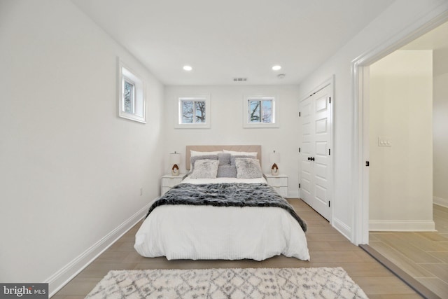 bedroom featuring baseboards, multiple windows, and wood finished floors