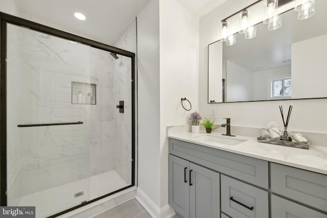 full bath featuring recessed lighting, vanity, baseboards, and a marble finish shower