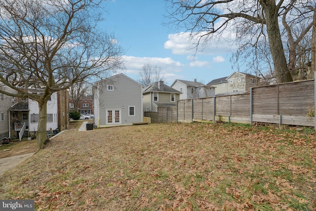 view of yard with french doors, fence, and a residential view