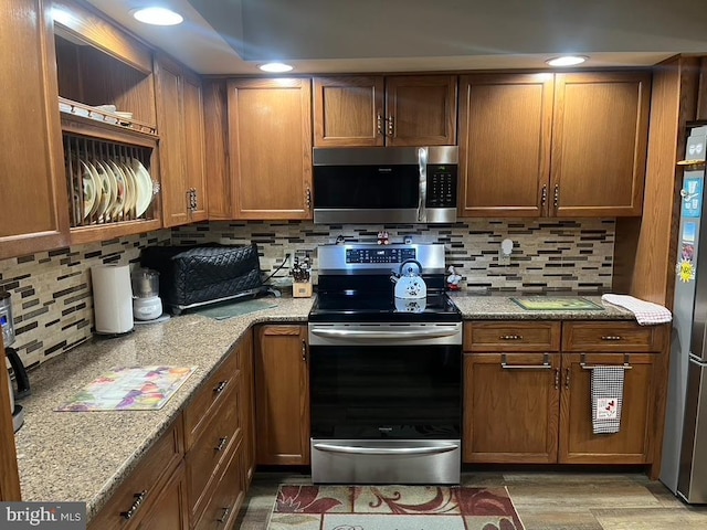 kitchen with backsplash, appliances with stainless steel finishes, and brown cabinetry