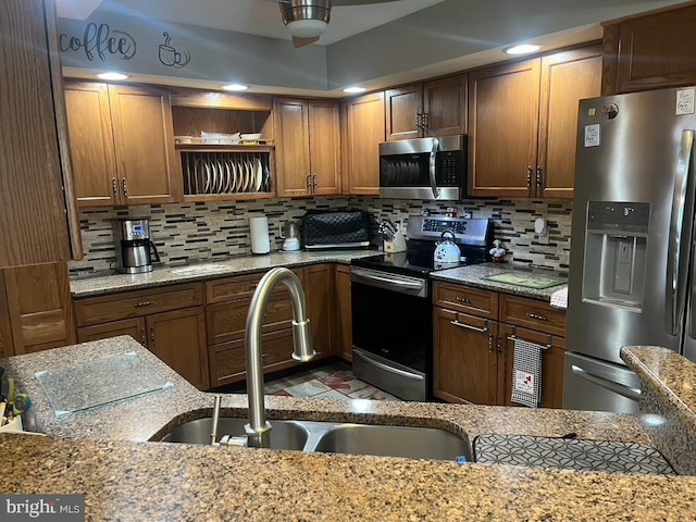 kitchen with brown cabinets, open shelves, appliances with stainless steel finishes, a sink, and decorative backsplash