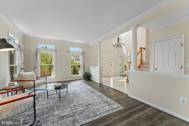 living room featuring dark wood-type flooring, ornate columns, a notable chandelier, and crown molding