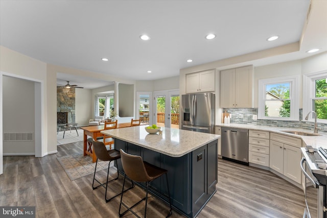 kitchen featuring light stone countertops, a sink, a kitchen breakfast bar, visible vents, and appliances with stainless steel finishes