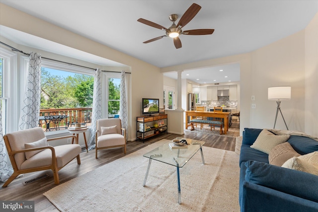 living room with visible vents, decorative columns, wood finished floors, and ceiling fan