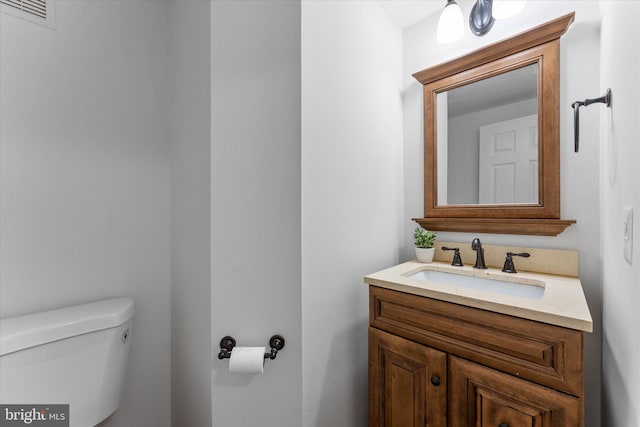 half bath featuring toilet, visible vents, and vanity