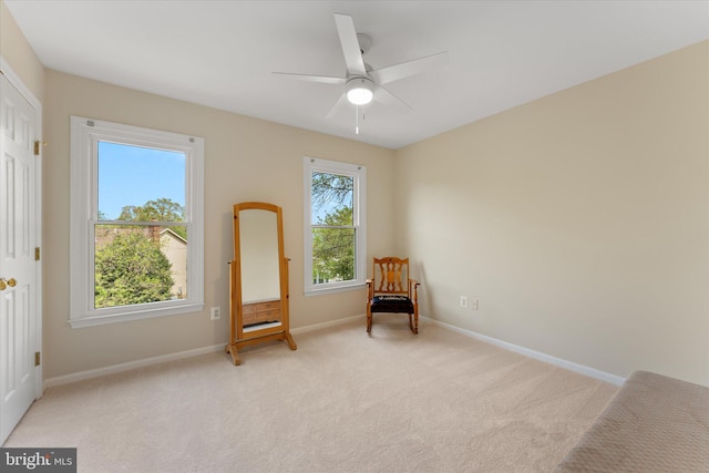 unfurnished room featuring light colored carpet, a ceiling fan, and baseboards