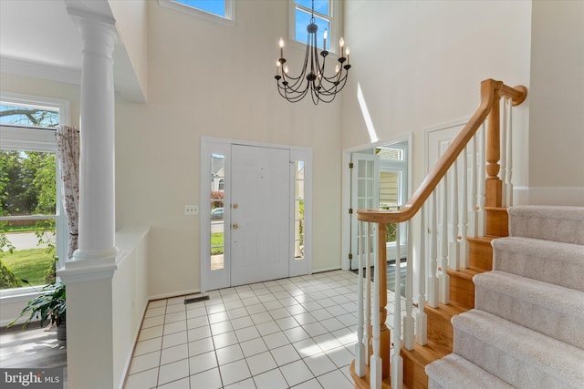 entrance foyer with a towering ceiling, ornate columns, stairway, and a healthy amount of sunlight
