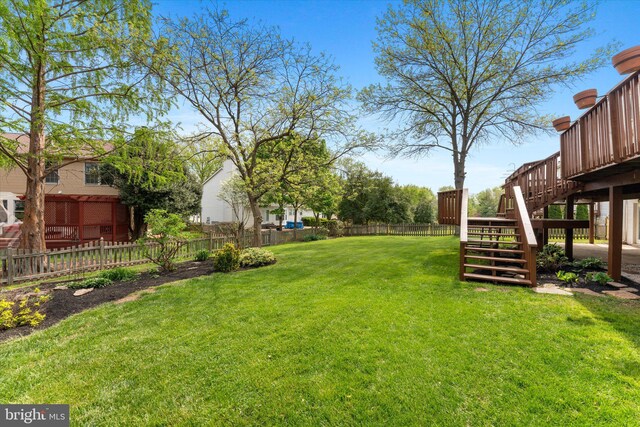 view of yard featuring fence, a wooden deck, and stairs