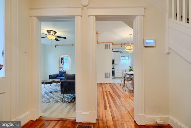 hall featuring a wealth of natural light, wood-type flooring, and visible vents