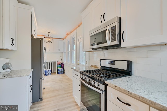 kitchen with decorative backsplash, light wood finished floors, white cabinetry, and stainless steel appliances