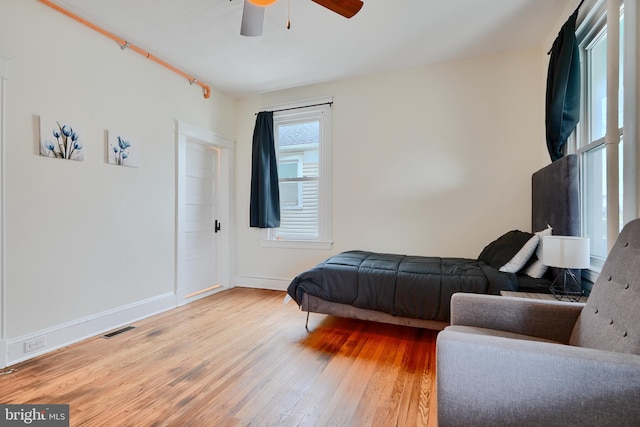 bedroom featuring visible vents, baseboards, a ceiling fan, and wood finished floors