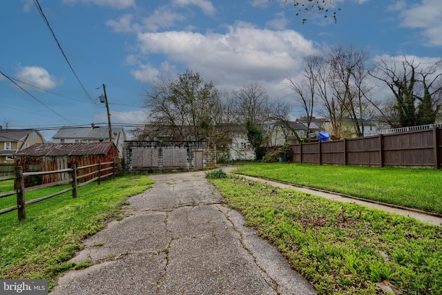 view of yard with aphalt driveway and fence private yard