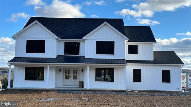 modern farmhouse with a porch, a standing seam roof, a shingled roof, and metal roof