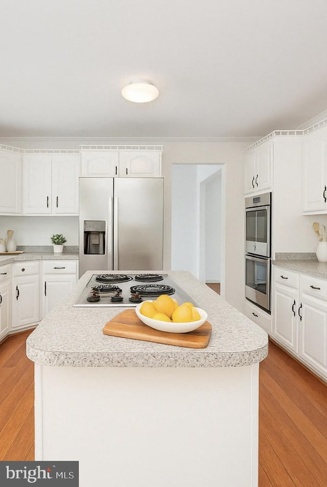 kitchen with white cabinetry, appliances with stainless steel finishes, a kitchen island, and light wood finished floors