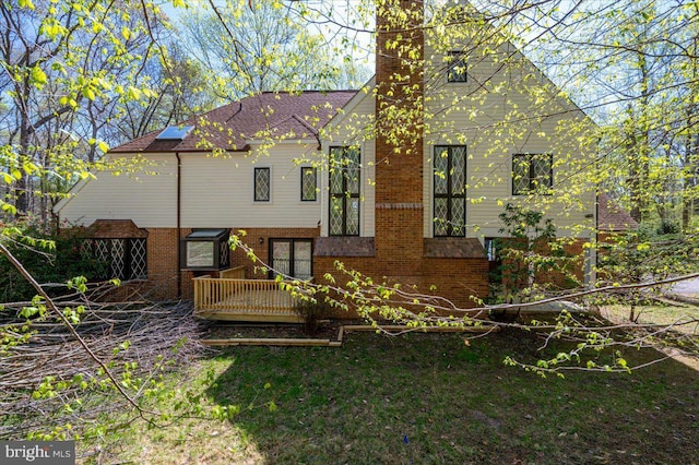 back of house with a chimney and brick siding