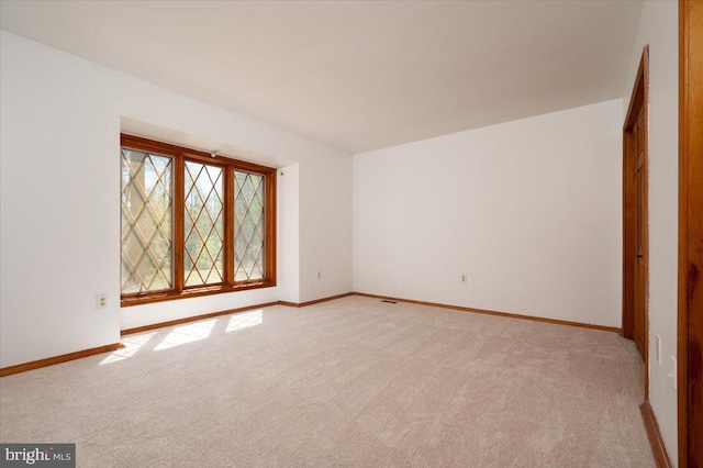 unfurnished room featuring light carpet and baseboards