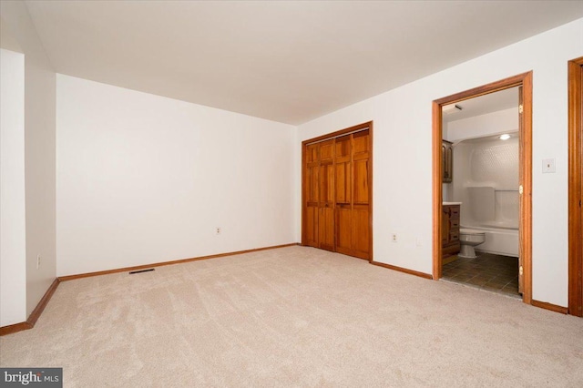 unfurnished bedroom featuring carpet flooring, visible vents, a closet, and baseboards