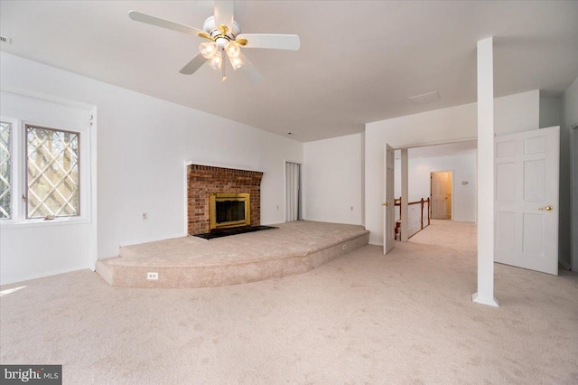 unfurnished living room with light colored carpet, a fireplace, a ceiling fan, and visible vents