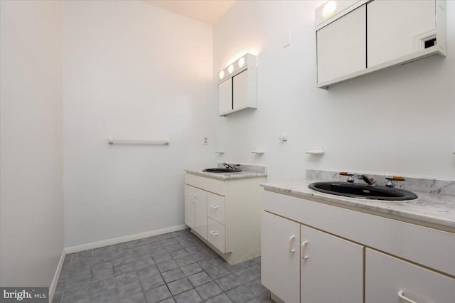 bathroom with two vanities, baseboards, and a sink