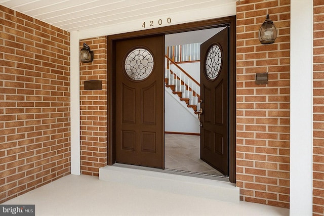 doorway to property with brick siding and covered porch