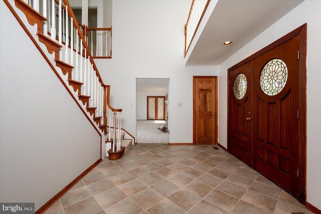 entrance foyer with recessed lighting, stairway, a towering ceiling, and baseboards